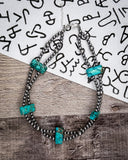 Necklace with turquoise stones on a wooden surface with a patterned background
