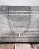 Necklace with pink conch on a wooden surface