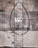 Necklace on a wooden surface with a ruler for scale