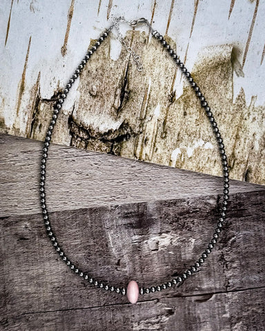 Necklace with pink conch on a wooden surface