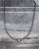 Silver beaded necklace on a textured surface