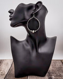 Black mannequin head with hoop earrings on a wooden surface