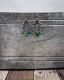 Teardrop-shaped earrings with green turquoise on a metallic surface