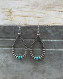 Pair of beaded earrings with turquoise beads on a textured surface