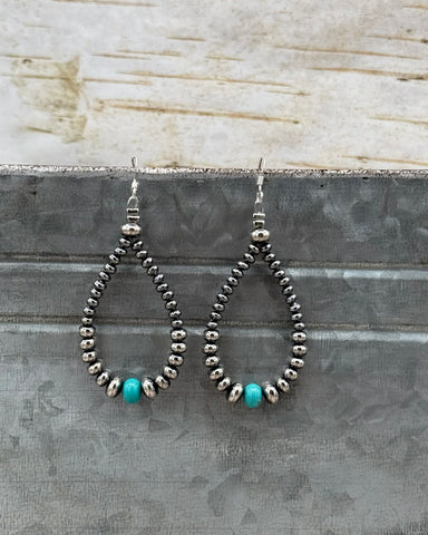 Pair of beaded earrings with turquoise beads on a textured surface