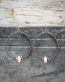 Hoop earrings with pink beads on a rustic wooden background
