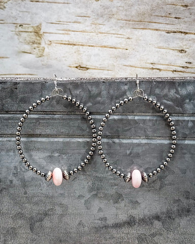 Hoop earrings with pink beads on a rustic wooden background