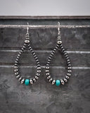 Pair of dangle hoop earrings with beads on a textured surface