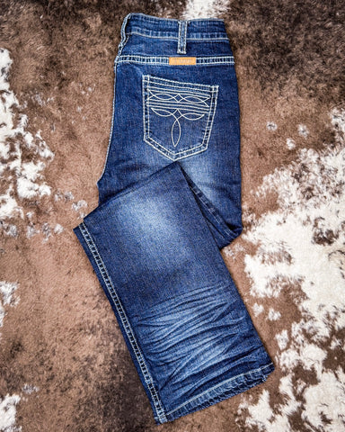 Folded blue jeans on a textured brown surface