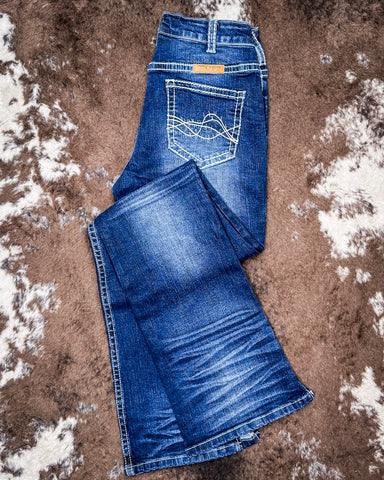 Folded blue jeans on a textured brown surface