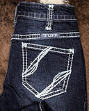 Close-up of a pair of blue jeans with 'TUFF' branding on a brown textured background