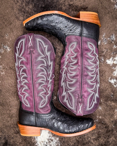 Purple and black ostrich cowboy boots on a textured surface