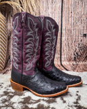 Purple and black ostrich cowboy boots on a textured surface
