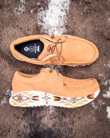 Tan shoes with a patterned sole on a textured surface