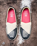 Pair of white and black checkered shoes with red insoles on a textured surface
