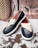 Pair of black and white checkered loafers on a textured surface with a rustic background.