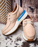 Pair of beige shoes with a blue sole accent on a textured surface