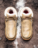 Pair of beige leather shoes with fur lining on a textured surface