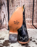 Black leather cowboy boot with tan insole on a wooden background