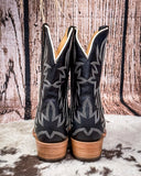 Black cowboy boots with white patterns on a wooden background
