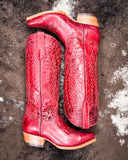 Red cowboy boots with intricate patterns on a textured surface