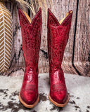 Red cowboy boots with intricate designs on a wooden background
