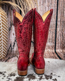 Red cowboy boots with brown soles on a rustic background