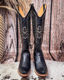 Pair of black cowboy boots with intricate designs on a wooden background