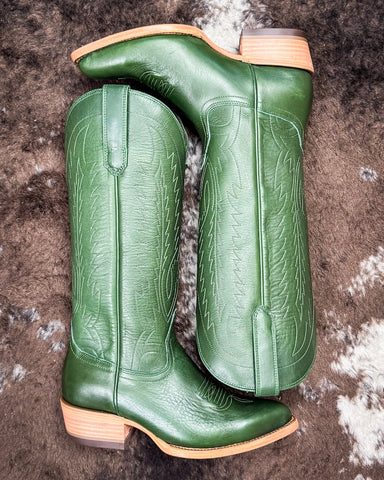 Pair of green leather boots on a textured surface