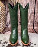 Green cowboy boots with brown soles on a wooden surface