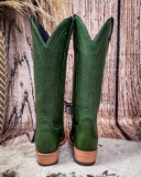 Green cowboy boots with brown soles on a wooden background
