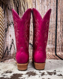 Western boots on cowhide rug, boot stitch design on boots, brown fence in background 