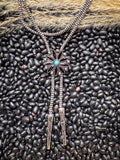 Close-up of turquoise concho bolo tie on black bean background with pampas grass accent