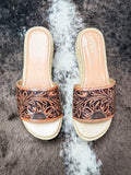 Close-up of floral engraved leather wedge sandals with natural jute platform sole.
