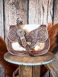 Western leather shoulder bag with cowhide accents and floral tooling with buckle detail