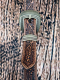 Close-up of tooled leather belt with engraved western-style brass buckle