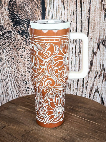 Western travel tumbler with floral engraving and handle view.

