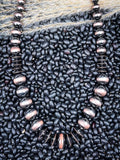 Brushed copper faux Navajo pearl necklace displayed on natural black beans and dried grass.