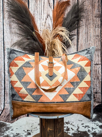 Weekender bag with shoulder strap displayed on a wood background