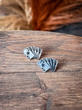 Stud earrings displayed on wood with grass in the background