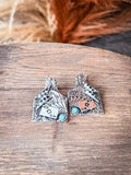 Earrings displayed on wood with decorative grass in the background