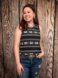 Model wearing tank top standing in front of a wood background.
