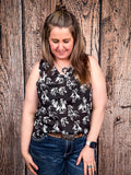 Model wearing tank top standing in front of a wood background.