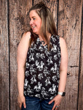 Model wearing tank top standing in front of a wood background.