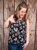 Model wearing tank top standing in front of a wood background.