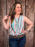 Model in front of a wood background wearing the Sunstripe Serape Tank Top styled with a belt.