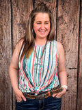 Model in front of a wood background wearing the Sunstripe Serape Tank Top tied in a knot.