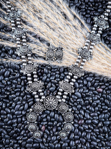 Necklace and earrings displayed on wheat and beans.