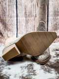 Sole  view of the Addie Glitter Knee High Boot in Taupe By Very G on a wood backdrop.