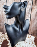 Trailblazer Concho Fashion Stud heart earring on a mannequin, sitting on cowhide, wood back drop.